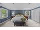Main bedroom with white trim and windows featuring a bed with pillows, lamps, and an ottoman at 2917 Rustic Ln, Charlotte, NC 28210