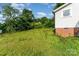 Grassy backyard with weeds and view of the exterior of a house at 307 Elm St, Belmont, NC 28012