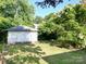 Backyard with a detached garage, grassy lawn, mature trees, and lush foliage, ideal for outdoor activities at 309 S Greene St, Wadesboro, NC 28170