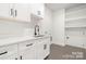 Bright laundry room featuring white cabinetry, gray flooring, modern black hardware, and sink at 3119 Shenandoah Ave, Charlotte, NC 28205