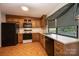 View of the kitchen with wood cabinets, black appliances, and a window with a green and white checkered valance at 3221 5Th Street Nw Ct, Hickory, NC 28601