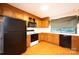 A full kitchen view with wooden cabinetry, black appliances, and a window with a green and white checkered valance at 3221 5Th Street Nw Ct, Hickory, NC 28601