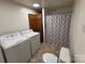 Bathroom with a toilet, shower with curtain, washer and dryer at 490 County Line Rd, Stony Point, NC 28678