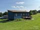 Charming blue home featuring a small deck and a well-manicured lawn in a tranquil setting at 490 County Line Rd, Stony Point, NC 28678