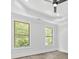 Bright bedroom featuring a tray ceiling, wood floors, and large windows with a view of trees at 5217 Waterfall Ct, Gastonia, NC 28056