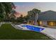 Backyard view featuring a lit pool at dusk, green lawn, and elegant patio with outdoor seating at 5638 Timber Ln, Charlotte, NC 28270