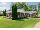 Charming brick home with a lush green lawn, well-manicured hedges, and a welcoming front porch with an American flag at 628 Stamie Dr, Chester, SC 29706