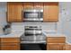 Close-up showcases stainless steel appliances, including a microwave and oven with wooden cabinets and white backsplash at 7212 Morsey Ct, Charlotte, NC 28269