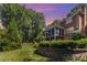 Manicured backyard with lush landscaping surrounding a brick home with a screened in porch at 905 Mangionne Dr, Matthews, NC 28105
