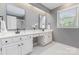 Bright bathroom with double sinks, modern faucets, a window, and white cabinets at 905 Mangionne Dr, Matthews, NC 28105