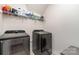 Well-lit laundry room with modern washer and dryer units, storage shelves, and tiled floors at 9274 Dunwich Dr, Gastonia, NC 28056