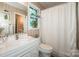 Bright bathroom featuring a white vanity, neutral wallpaper, and decorative window accents at 928 Tally Ho Ct, Charlotte, NC 28212