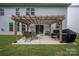 Backyard patio has a covered pergola, a dining set, a grill, and lush green grass at 1054 Thoroughbred Dr, Iron Station, NC 28080
