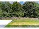 A backyard with a retaining wall, grass lawn, and mature trees at 12829 Brandenburg Ln, Midland, NC 28107