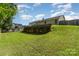 A beautiful green backyard with a wooden retaining wall and fence under a blue sky with puffy clouds at 12829 Brandenburg Ln, Midland, NC 28107