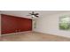 A carpeted bedroom with a ceiling fan, red accent wall, and two windows at 12829 Brandenburg Ln, Midland, NC 28107