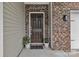 Classic brown front door with brick accents and potted plants creating a warm, welcoming entrance at 1349 Bridgeford Nw Dr, Huntersville, NC 28078