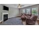 Cozy living room with a fireplace, ceiling fan, plush seating, and lots of natural light at 1349 Bridgeford Nw Dr, Huntersville, NC 28078