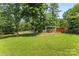 Large, lush green backyard with swing set, small storage building, bench, and wooden fence at 14402 Raynham Dr, Charlotte, NC 28262