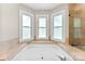 Bright and spacious bathroom features a relaxing soaking tub with three windows and a tiled surround at 14402 Raynham Dr, Charlotte, NC 28262