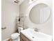 Modern half bathroom featuring a stylish vanity, round mirror, and tiled floors at 14402 Raynham Dr, Charlotte, NC 28262