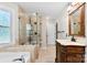 Bright bathroom features a glass shower, a soaking tub, and an elegant vanity with a marble countertop at 14402 Raynham Dr, Charlotte, NC 28262