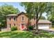 Charming two-story brick home with a manicured lawn, bright red door, and attached two-car garage at 14402 Raynham Dr, Charlotte, NC 28262