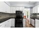 Modern kitchen featuring black appliances, white cabinetry, and granite countertops, perfect for cooking and entertaining at 14402 Raynham Dr, Charlotte, NC 28262