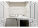 Bright laundry room with modern, white washer and dryer and wire shelving for extra storage space at 14402 Raynham Dr, Charlotte, NC 28262