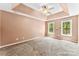 Spacious main bedroom with a trey ceiling, ceiling fan, carpet flooring, and two windows for plenty of natural light at 14402 Raynham Dr, Charlotte, NC 28262