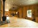 Open-concept living room with wood paneling, fireplace, and modern kitchen appliances, offering a rustic feel at 1640 Bear Poplar Rd, Cleveland, NC 27013