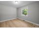 Bedroom features light gray walls, white trim, wood-look flooring, and a window view at 1709 Masonic Dr, Charlotte, NC 28205