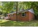 Quaint brick home with a lush green lawn and mature trees, featuring blue shutters and a cozy entrance at 1709 Masonic Dr, Charlotte, NC 28205