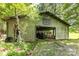 Well-maintained barn with equipment inside and an open front, set in a wooded area at 2159 Quiet Cove Ln, Stanfield, NC 28163