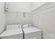Functional laundry room with a white washer, dryer and overhead shelving for storage at 2321 Oberwood Dr, Charlotte, NC 28270
