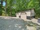 Spacious metal garage with two doors on a tree-filled lot, perfect for storing vehicles and equipment at 2345 Stallings Rd, Matthews, NC 28104