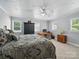 Comfortable bedroom with a patterned comforter, a ceiling fan, and natural light from the windows at 2345 Stallings Rd, Matthews, NC 28104