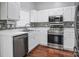 Kitchen boasts stainless steel appliances, white cabinets, mosaic backsplash and hardwood floors at 2467 Hawk Ridge Dr, Gastonia, NC 28056