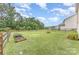 Large, fenced backyard with a grassy lawn, planting bed and fire pit at 3304 Saddlebrook Dr, Midland, NC 28107