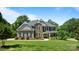 Charming two-story home with a stone and brown exterior, complemented by a lush green lawn and mature trees at 3963 Harmattan Dr, Denver, NC 28037