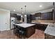 Spacious kitchen features dark wood cabinetry, granite countertops, and a central island with seating at 3963 Harmattan Dr, Denver, NC 28037