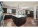 Open kitchen featuring dark cabinets, granite countertops, island seating, and hardwood flooring at 3963 Harmattan Dr, Denver, NC 28037
