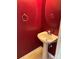 Compact bathroom with a pedestal sink, round mirror, and bright red accent wall at 5650 Kimmerly Woods Dr, Charlotte, NC 28215