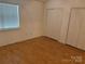 Bedroom with hardwood floors, a large window, and a spacious double-door closet at 5650 Kimmerly Woods Dr, Charlotte, NC 28215