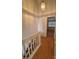 Hallway with wood floors, white banister, and view into a bedroom at 5650 Kimmerly Woods Dr, Charlotte, NC 28215