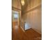 Hallway with wooden floors, white banister, and view into a bedroom at 5650 Kimmerly Woods Dr, Charlotte, NC 28215