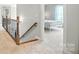 Hallway with wood railing staircase leading to a bedroom with a white iron frame bed and soft natural lighting at 5916 Four Wood Dr, Matthews, NC 28104