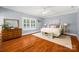 Bright bedroom features hardwood floors, white trim, a ceiling fan, and plantation shutters on the windows at 6422 Northern Red Oak Dr, Mint Hill, NC 28227
