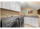Functional laundry room with modern washer and dryer, and a convenient utility sink and storage at 6422 Northern Red Oak Dr, Mint Hill, NC 28227