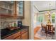 Elegant wet bar with granite countertop, glass-door cabinets, and seamless flow to a dining area at 6422 Northern Red Oak Dr, Mint Hill, NC 28227